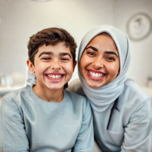 دكتورة ريم شهاب تبتسم مع مريض يرتدي تقويم أسنان بألوان زاهية في عيادتها بالقنفذة.